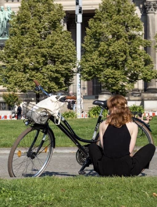 a woman sitting on the grass next to a bike