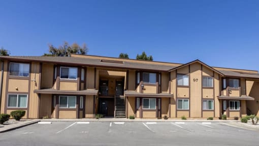 the front of an apartment building with a parking lot