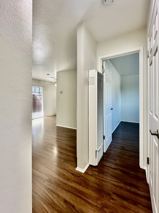 an empty living room and hallway with wood flooring and a white refrigerator