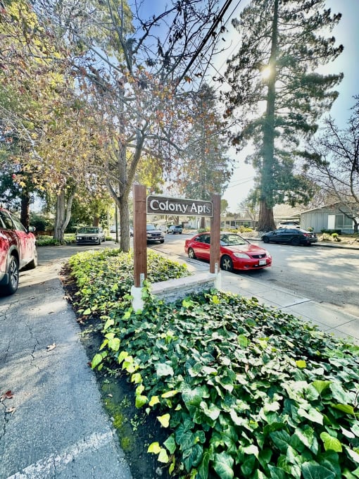 a sign for colony apartments on the side of a street