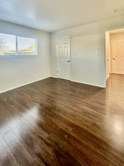 an empty living room with wood flooring and a window