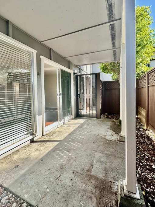 a long walkway leading to a house with a glass door and a door open