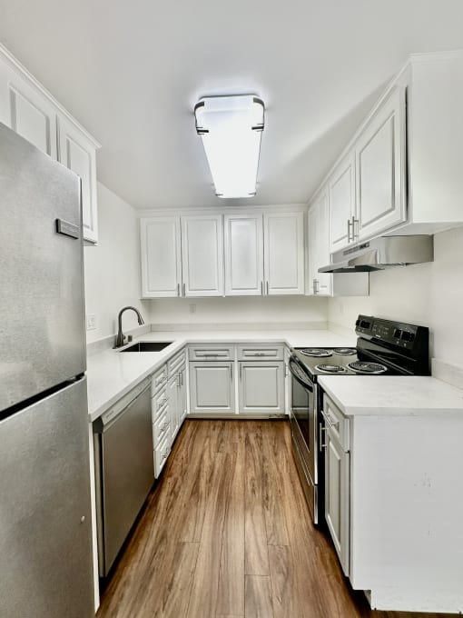 an empty kitchen with white cabinets and stainless steel appliances