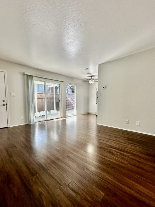 an empty living room with wood floors and a sliding glass door