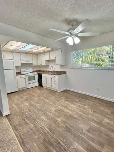 A kitchen with white cabinets and a fan on the ceiling.