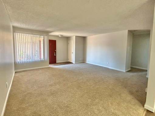 A room with a carpeted floor and a red door.