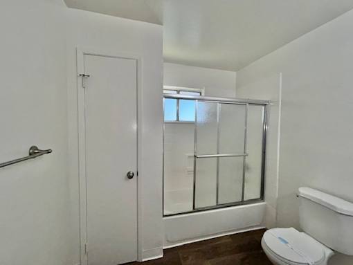 A white bathroom with a toilet, shower, and sink.