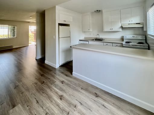an empty kitchen with white cabinets and a white counter top