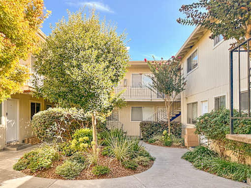 A sunny day at a residential area with apartment buildings and a well-maintained garden.