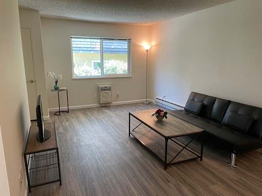 A living room with a black leather couch, a wooden coffee table, and a television.