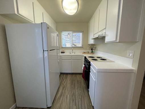 A small white kitchen with a refrigerator, stove, and sink.