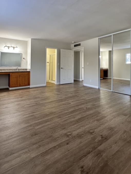 an empty living room with wood floors and a tv
