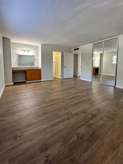an empty living room with wooden floors and a tv