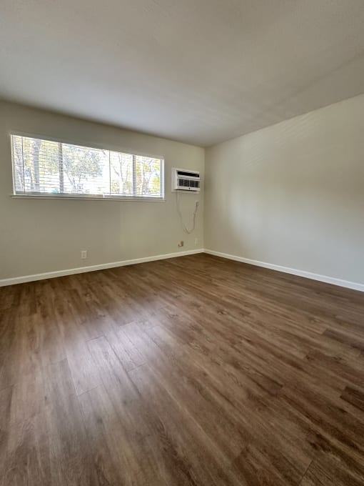 an empty living room with wooden floors and a window