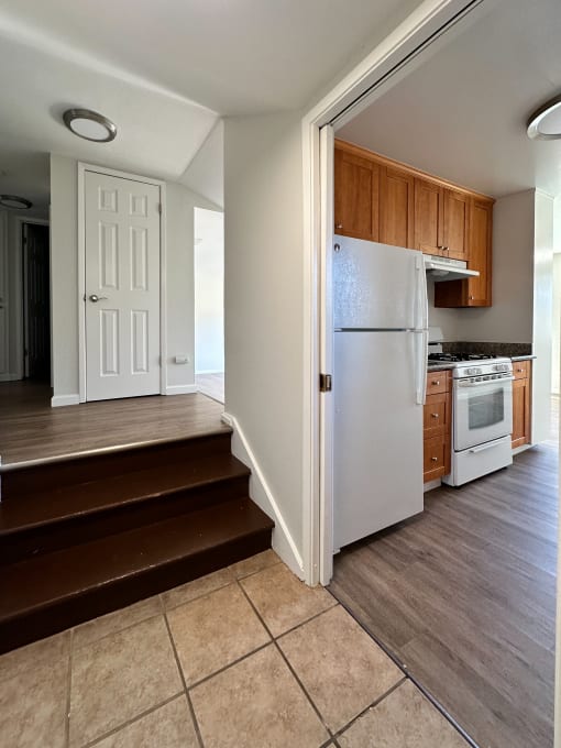 a kitchen with a white refrigerator and stove and a staircase