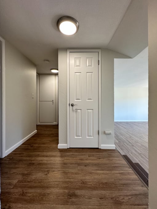 an empty hallway with a white door and wood flooring
