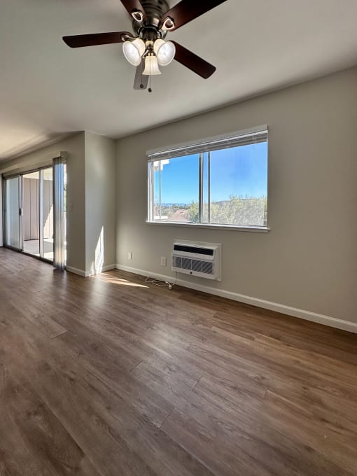an empty living room with a ceiling fan and a window