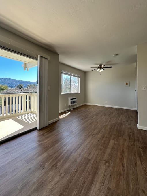 an empty living room with a balcony and a ceiling fan