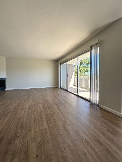 an empty living room with sliding glass doors to a balcony