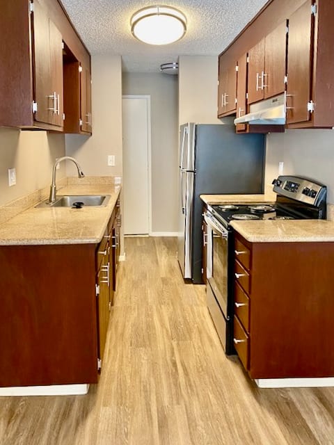 a kitchen with wood flooring and stainless steel appliances