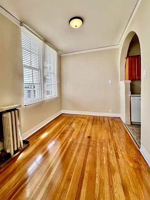 an empty living room with wood floors and an arched doorway