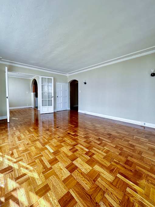 an empty living room with wood flooring and white walls