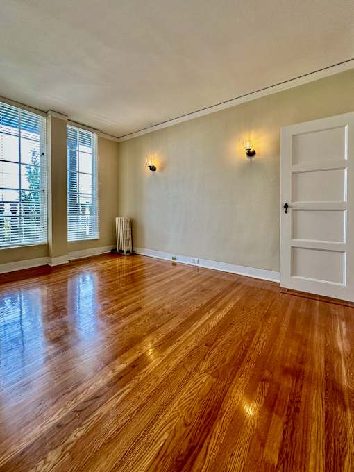an empty living room with wood floors and a white door