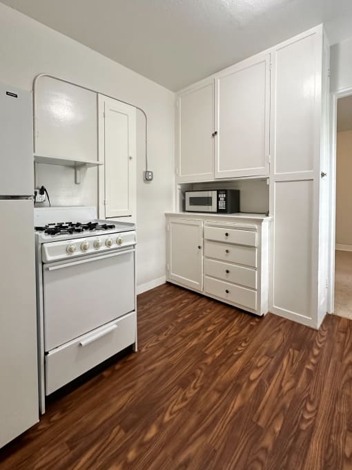 an empty kitchen with white cabinets and a stove and a refrigerator