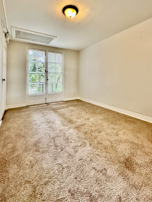 an empty living room with carpet and a window