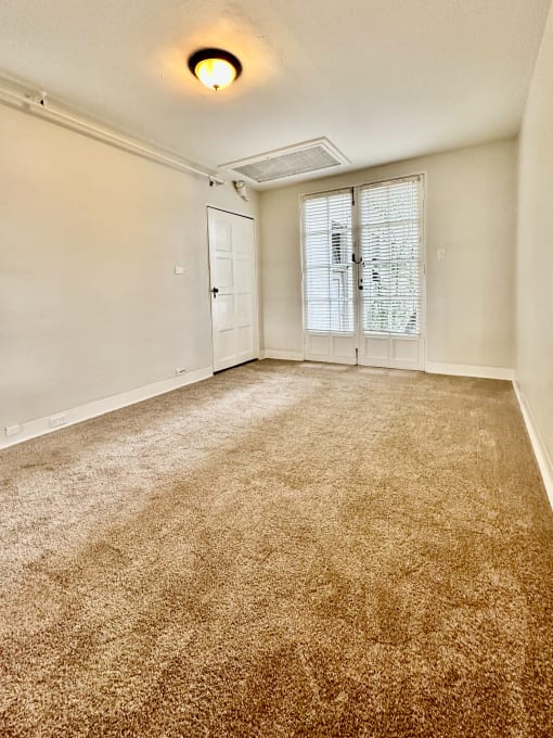 an empty living room with carpet and a door