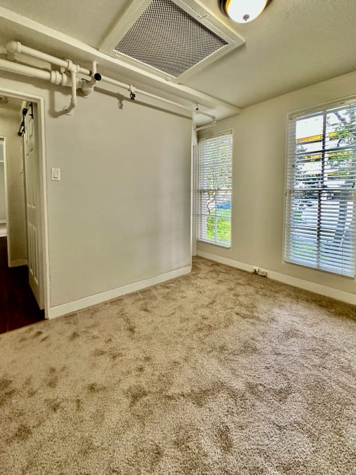 the living room of an empty home with a carpeted floor and a window