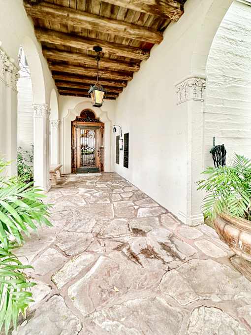 a hallway with stone floors and white walls and a wooden ceiling