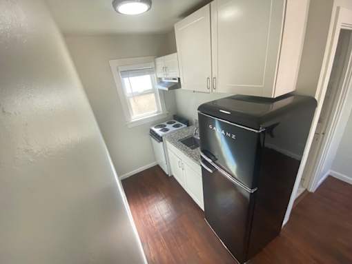 A small kitchen with a black fridge and white cabinets.