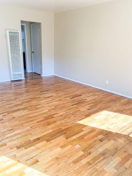 an empty living room with wood flooring and white walls