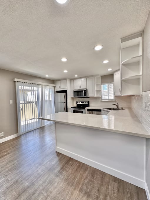 a kitchen and living room with a sliding glass door leading to a balcony