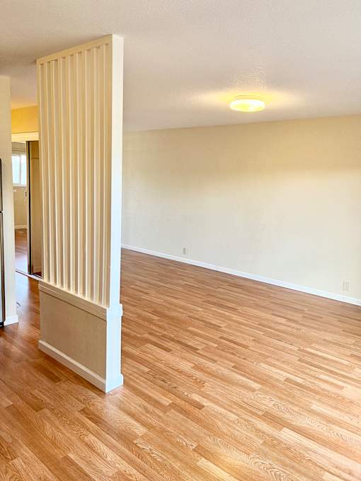 an empty living room with a radiator and hardwood floors