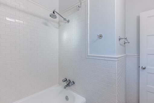 a white tiled bathroom with a shower and a sink