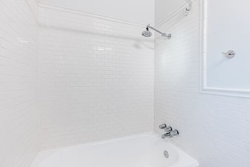 a white tiled bathroom with a shower and a tub