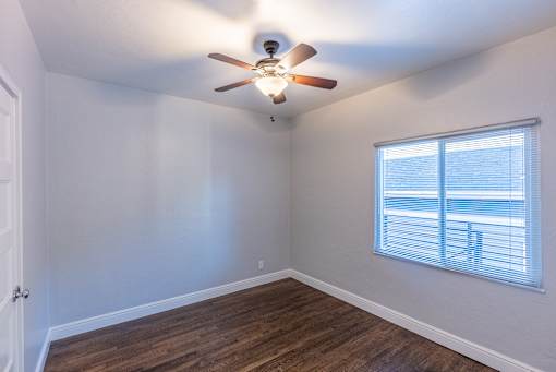 an empty room with a ceiling fan and a window