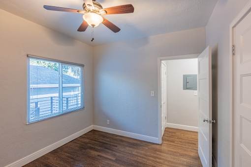 an empty bedroom with a ceiling fan and a window
