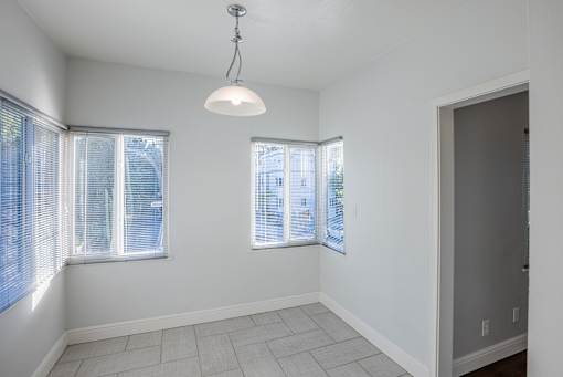 an empty living room with three windows and a door