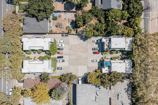 an aerial view of a parking lot with houses and trees