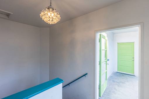 an empty room with a staircase and a green door