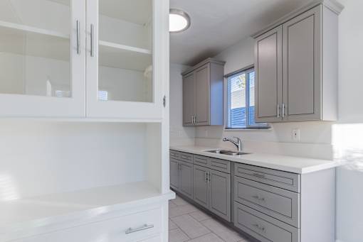 an empty kitchen with white cabinets and a sink