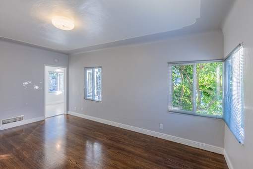 an empty living room with wood floors and a window