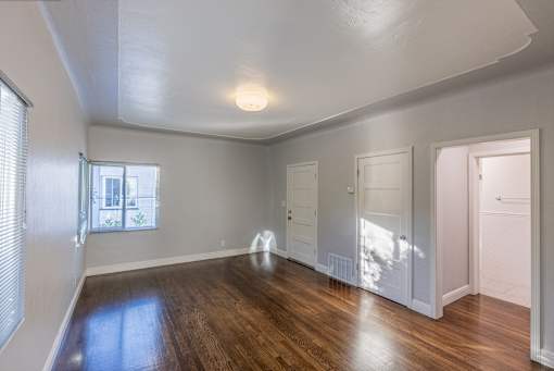 an empty living room with wood flooring and white walls