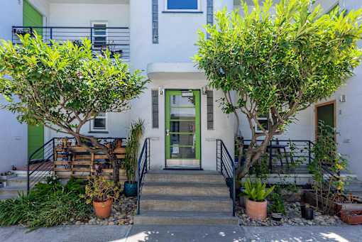 the front of a white building with stairs and a green door