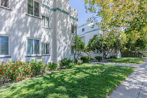 a white building with a lawn and trees in front of it