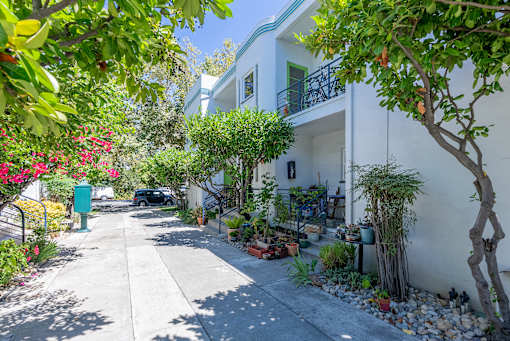 a white house with a sidewalk and plants in front of it