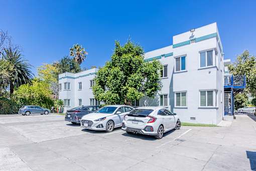 a white apartment building with three cars parked in front of it